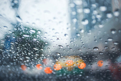 Driving car on road in the rain with raindrop over the wind shield, traffic jam in rainy season