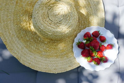 Close-up high angle view of strawberries in plate by hat on table
