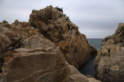 Rock formations on sea shore against sky