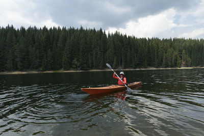 Woman kayaking in lake against sky