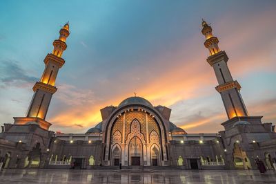 Low angle view of illuminated building against sky during sunset