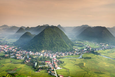 Aerial view of city and mountains against sky during sunset