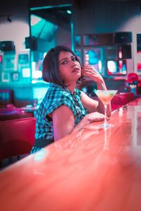 Portrait of woman drinking glass on table at restaurant