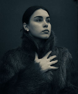 Portrait of young woman against black background