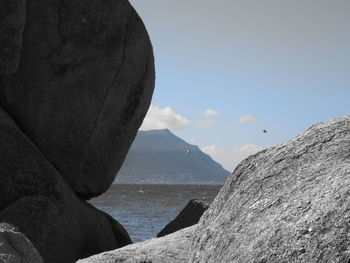 Scenic view of sea by mountains against sky