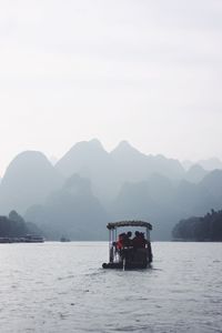 Boat sailing on sea against mountains