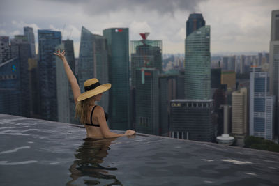 Woman in swimming pool against buildings in city