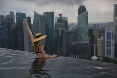Woman swimming in infinity pool against buildings