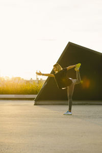 Full length of woman stretching on road