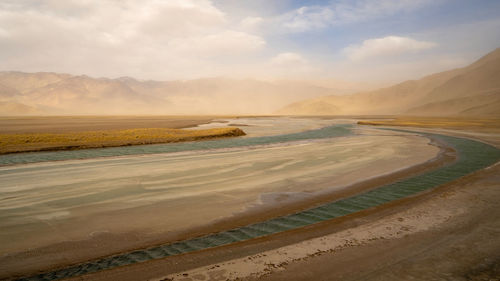 Scenic view of desert against cloudy sky