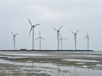 Windmills on field against sky