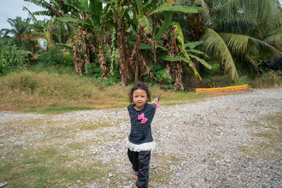 Portrait of girl holding malaysian flags on field 