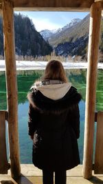 Rear view of woman looking at lake against mountain