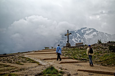 Rear view of men walking on mountain against sky