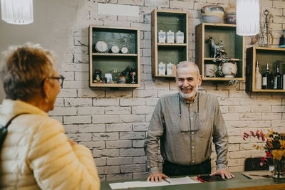 Happy senior owner greeting customer at home decor store