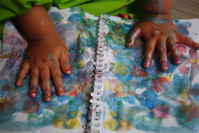 Cropped image of messy child hands over book