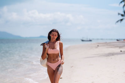 Young woman standing on beach against sky