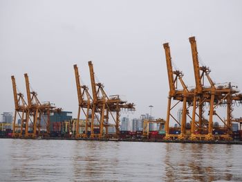 Cranes at commercial dock against clear sky