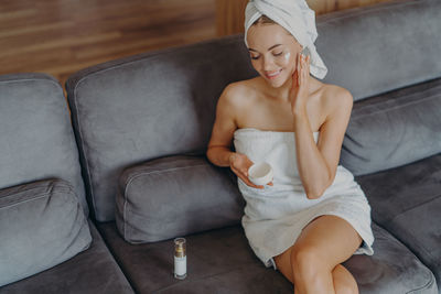 High angle view of woman smiling woman applying moisturizer on face