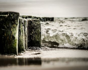 Surface level view of waves splashing on wooden posts at beach