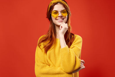 Portrait of smiling young woman against red background