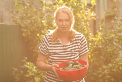 Portrait of smiling young woman holding potted plant
