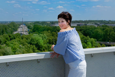 Smiling young woman standing against built structure