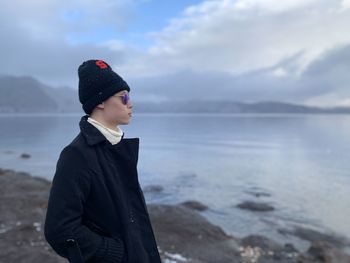 Man standing in sea against sky during winter