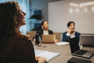 Happy businesswoman sitting at desk in board room