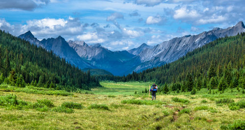 Rear view of man with bicycle on mountain against sky