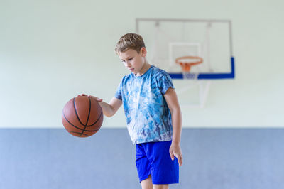 Boy playing with ball against blue background