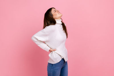 Young woman standing against yellow background