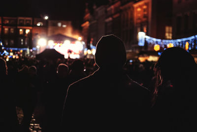 Rear view of people standing in city at night