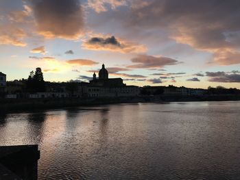 River in city against sky during sunset