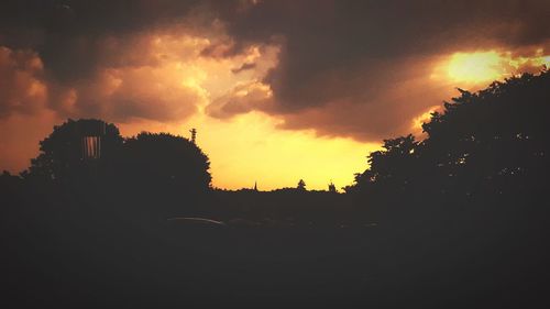 Silhouette trees on field against sky at sunset