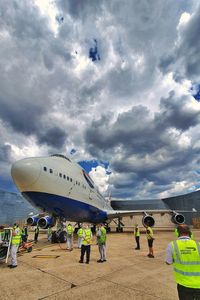 People at airplane against sky