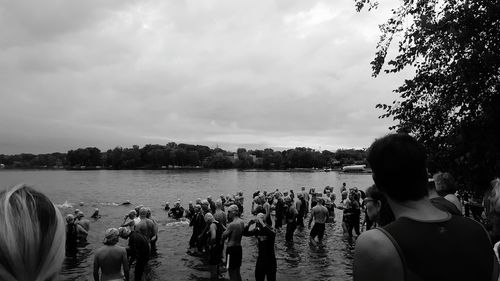 People standing on riverbank against sky