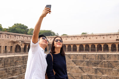 Couple taking selfie while standing against built structure