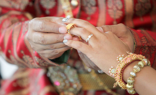 Midsection of wedding couple exchanging finger rings during ceremony