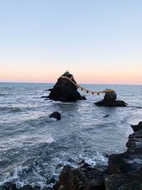 Rock formation on sea against sky during sunset