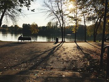 Park bench by lake against sky