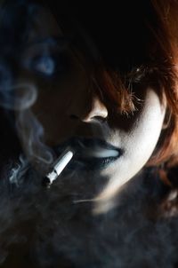 Portrait of young woman smoking cigarette in darkroom