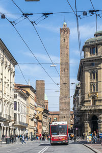 Cars on road by buildings against sky in city