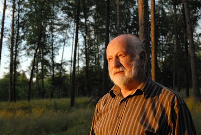 Thoughtful senior man standing in forest during sunset