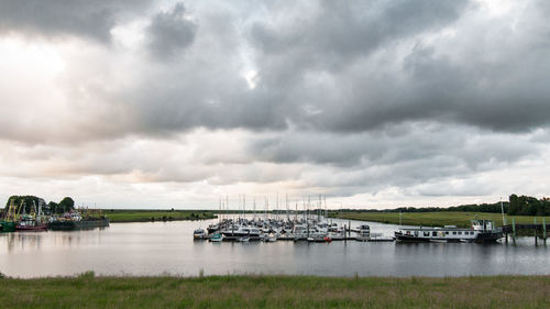 Boats in sea against cloudy sky