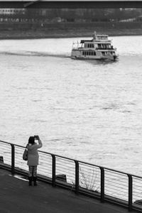 Rear view of woman standing on railing against sea