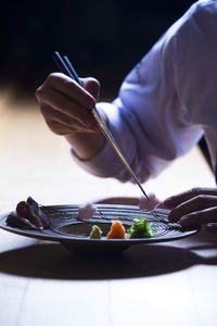 Midsection of man eating food in plate on table