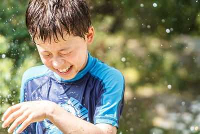 Water spraying over cheerful boy at yard