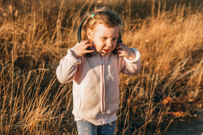 Little girl listening to music with headphones, funny kid, child on the street on a sunny autumn day