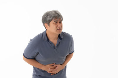 Man looking away while standing against white background
